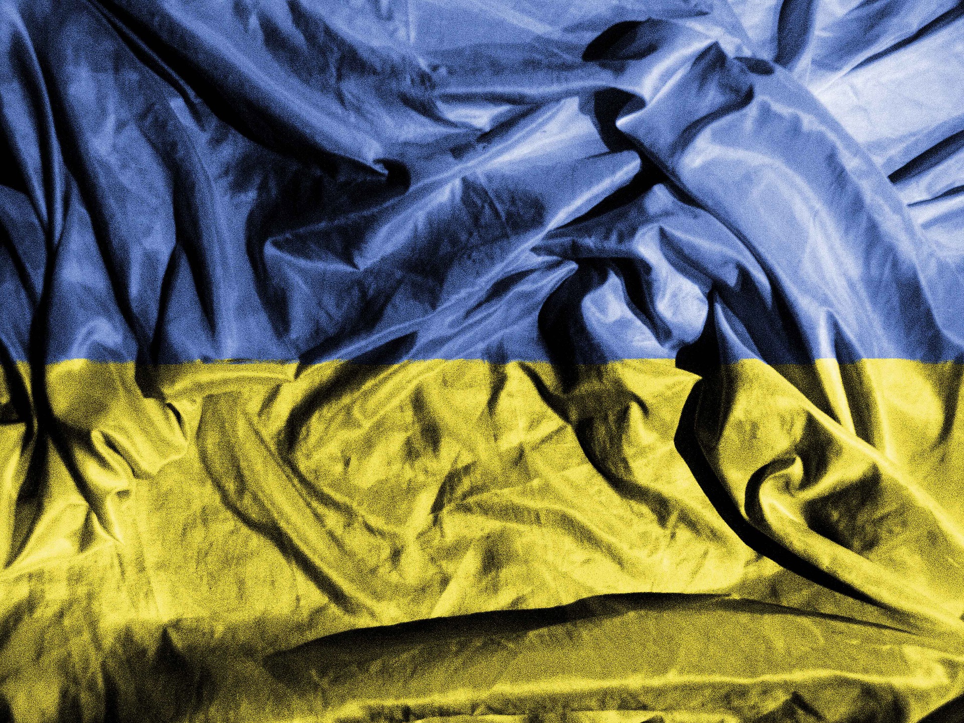Das Bild zeigt eine faltige ukrainische Flagge