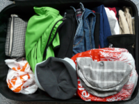 Das Bild zeigt einen mit Kleidung gepackten, offenen Koffer von oben